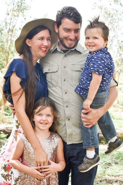 A family is posing for a picture together in a park.
