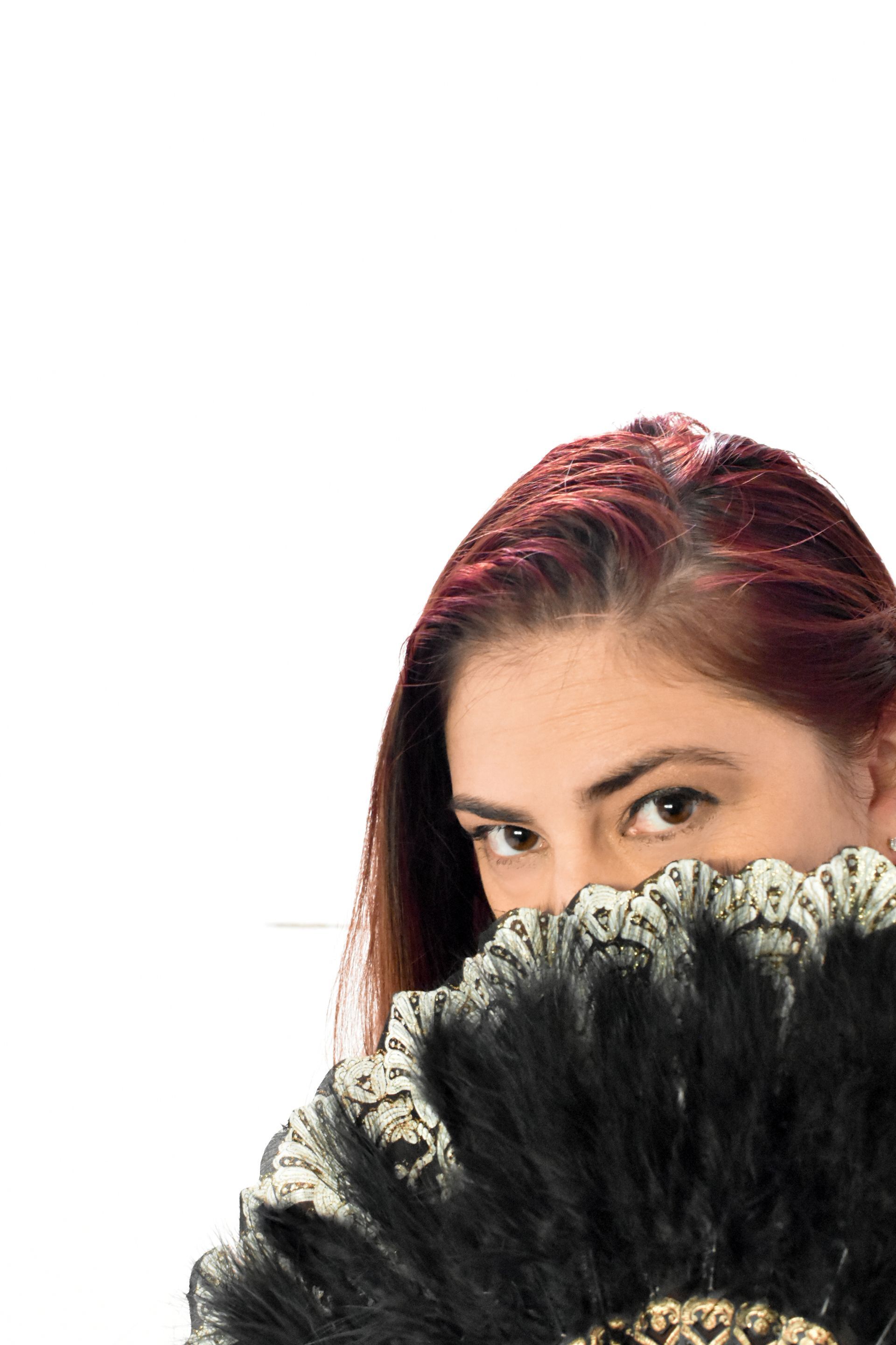 A woman is covering her face with a fan.