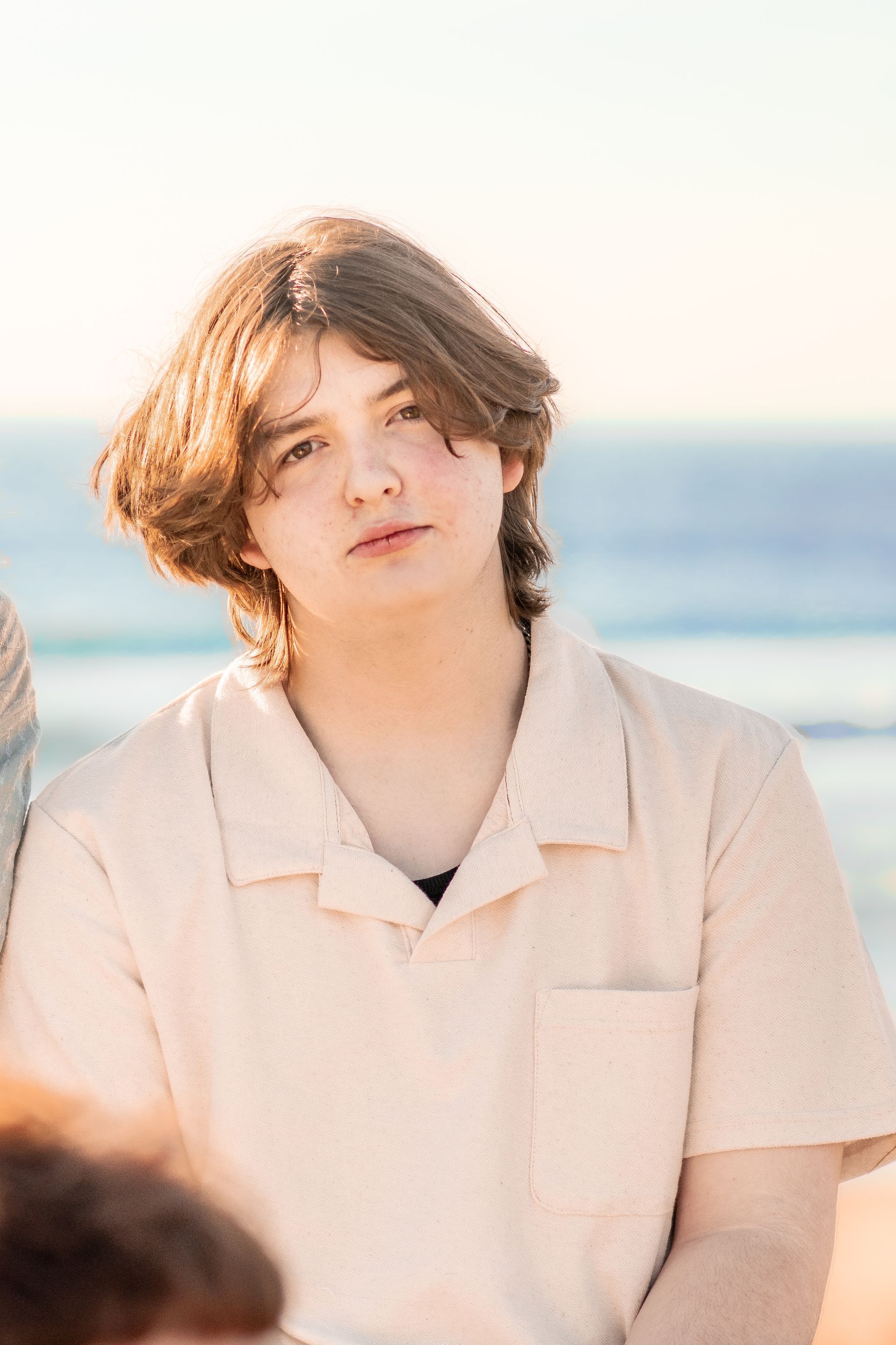 A young man is sitting on the beach looking at the camera. Senior. Graduate. 