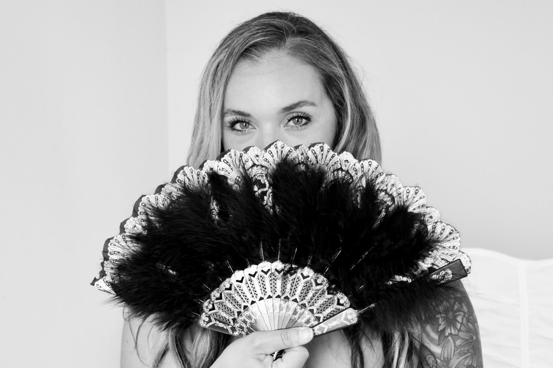 A woman is holding a fan in front of her face.