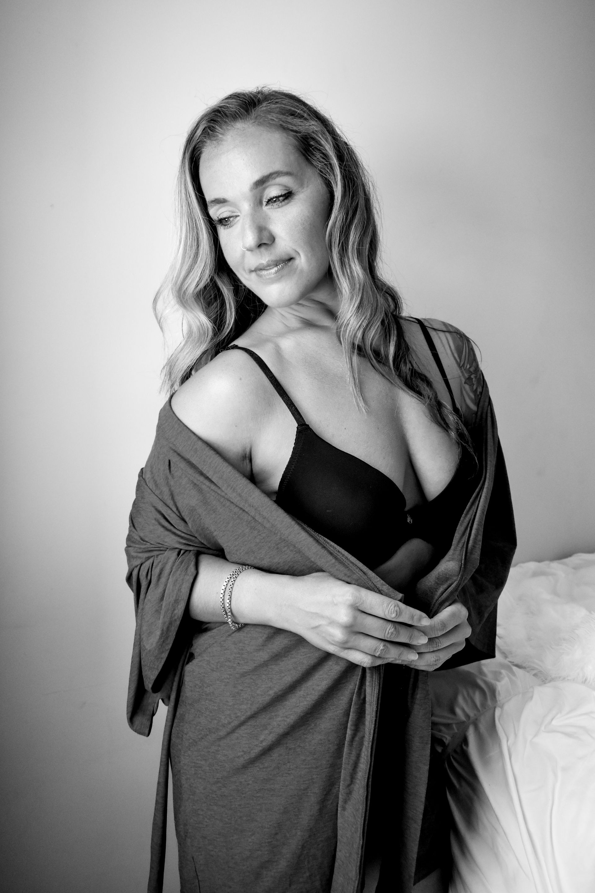 A black and white photo of a woman in lingerie and a robe. 