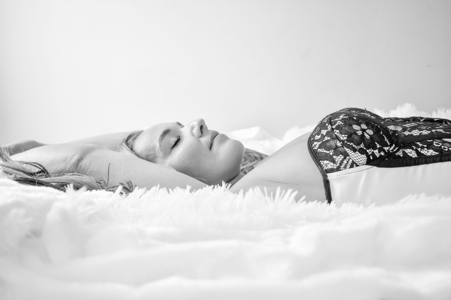 A woman is laying on a bed with her eyes closed.
