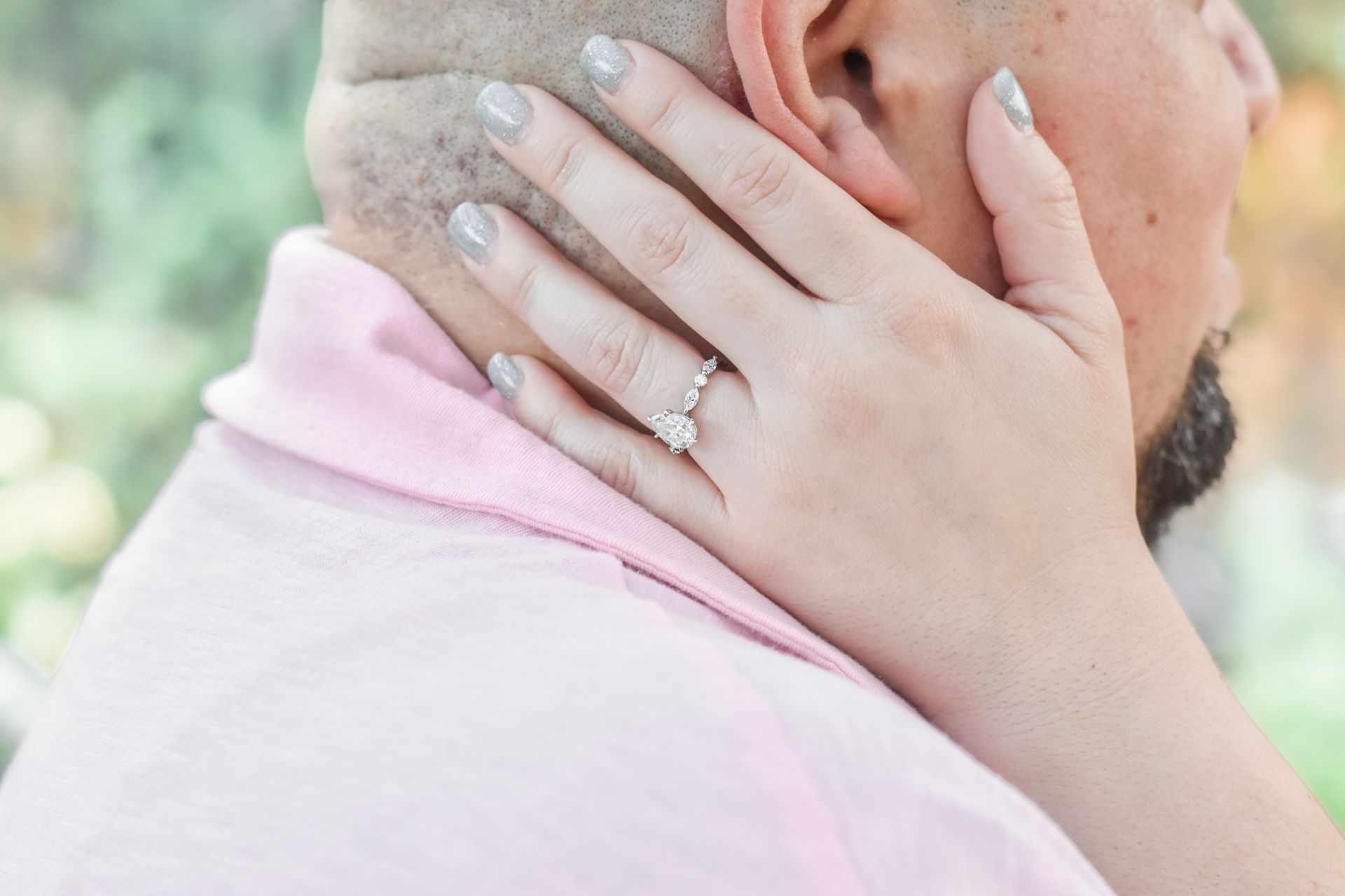 A close up of a woman 's hand with an engagement ring on her finger.