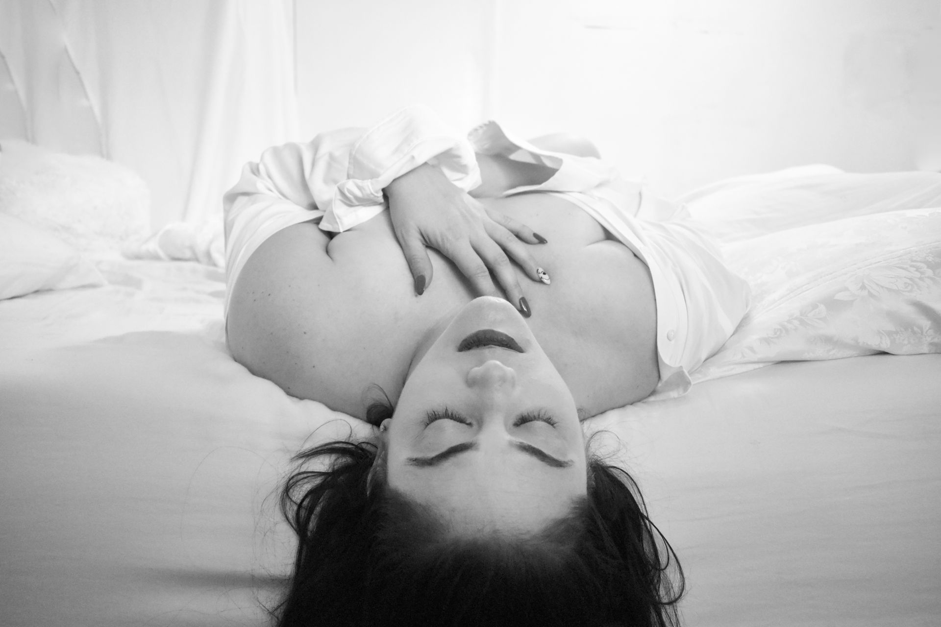 A woman is laying on a bed with her hands on her chest. SEXY