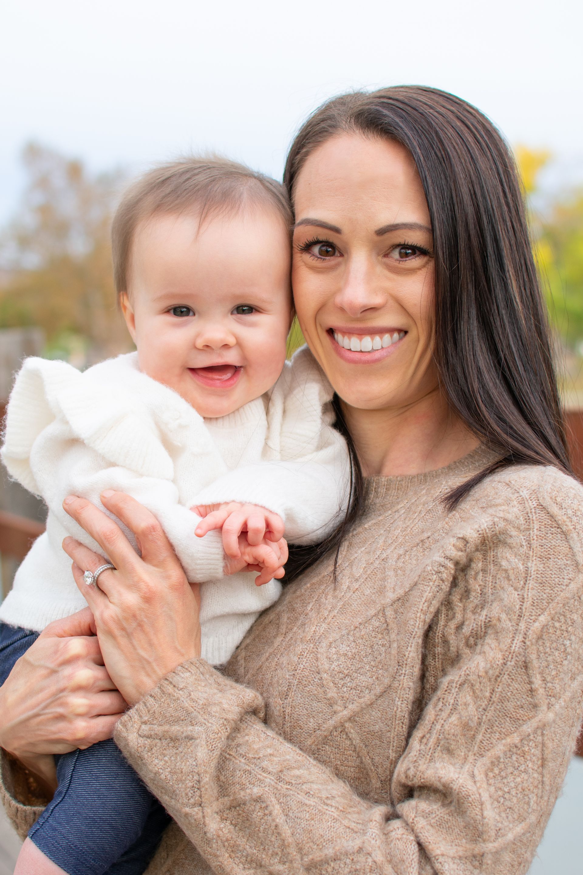 A woman is holding a baby in her arms and smiling. Family