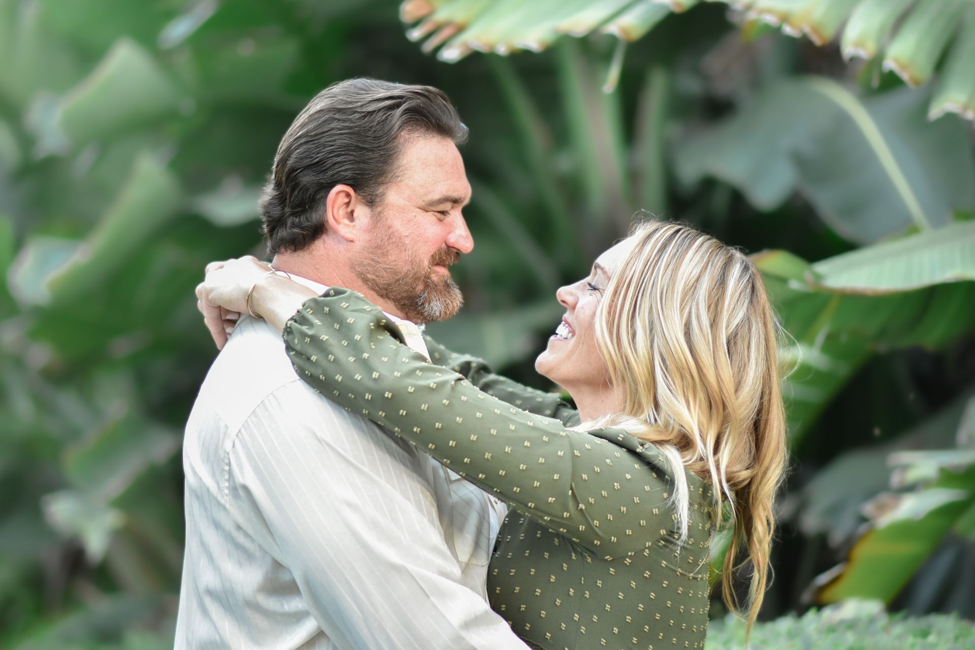 A man and a woman are hugging each other in a park.