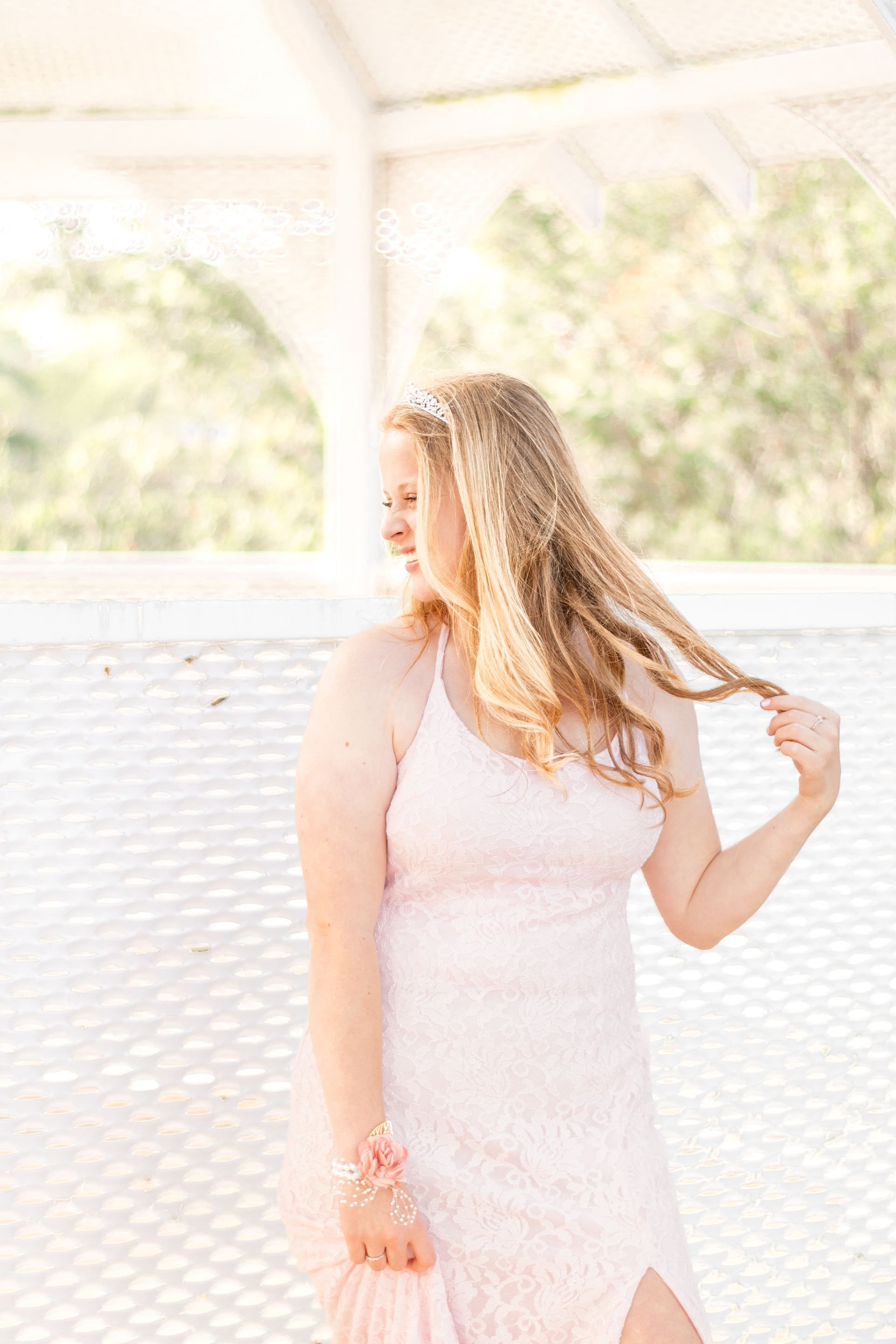 A woman in a pink dress is standing under a gazebo holding her hair in Rancho Palos Verdes