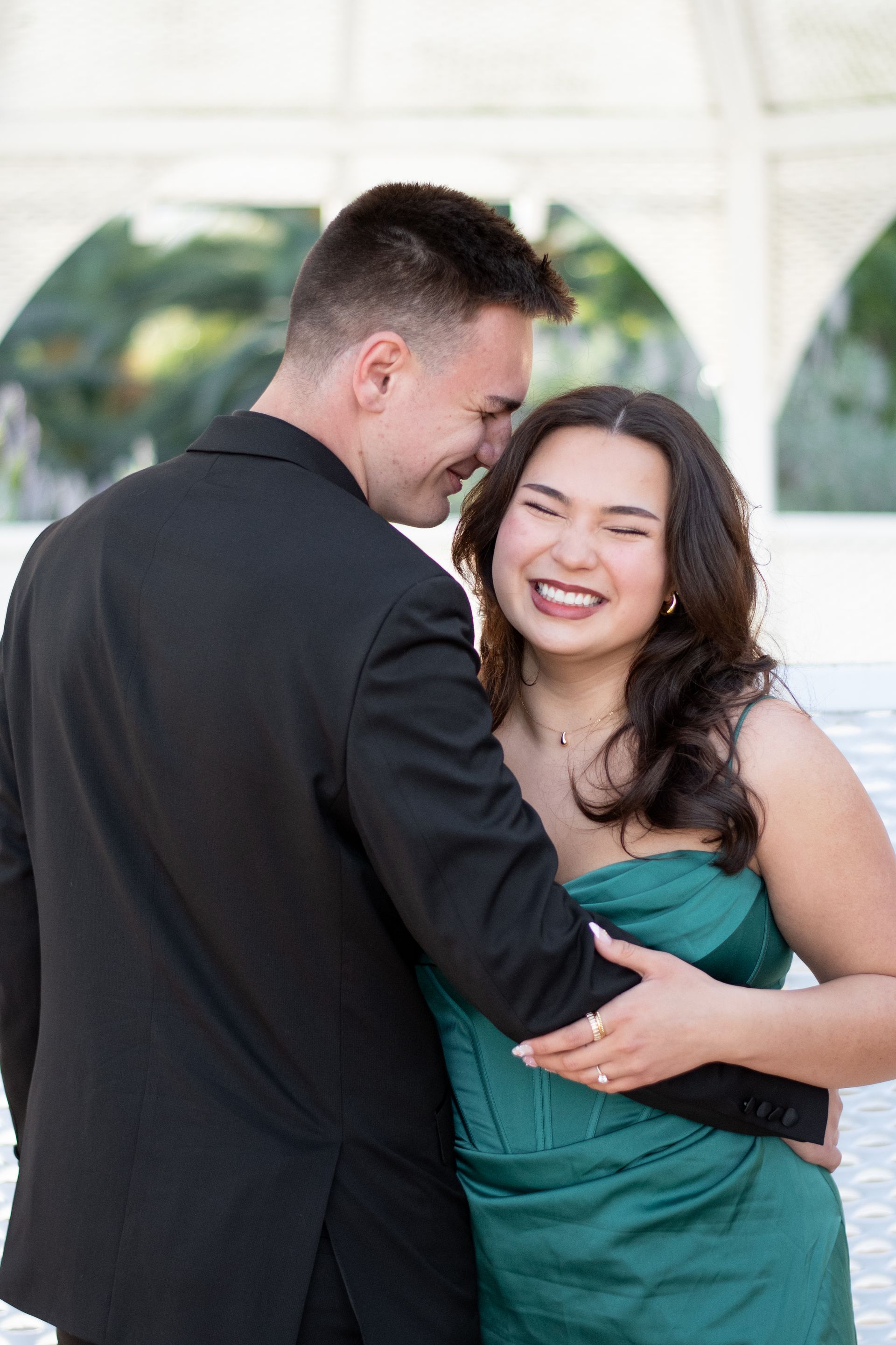 A man in a suit is hugging a woman in a green dress in Southern California