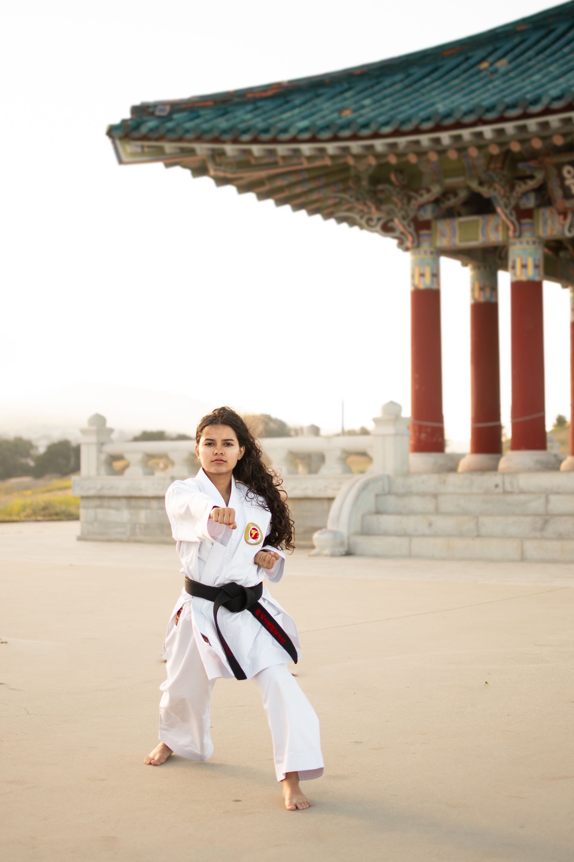 A woman is practicing karate in front of a temple near Point Fermin Park