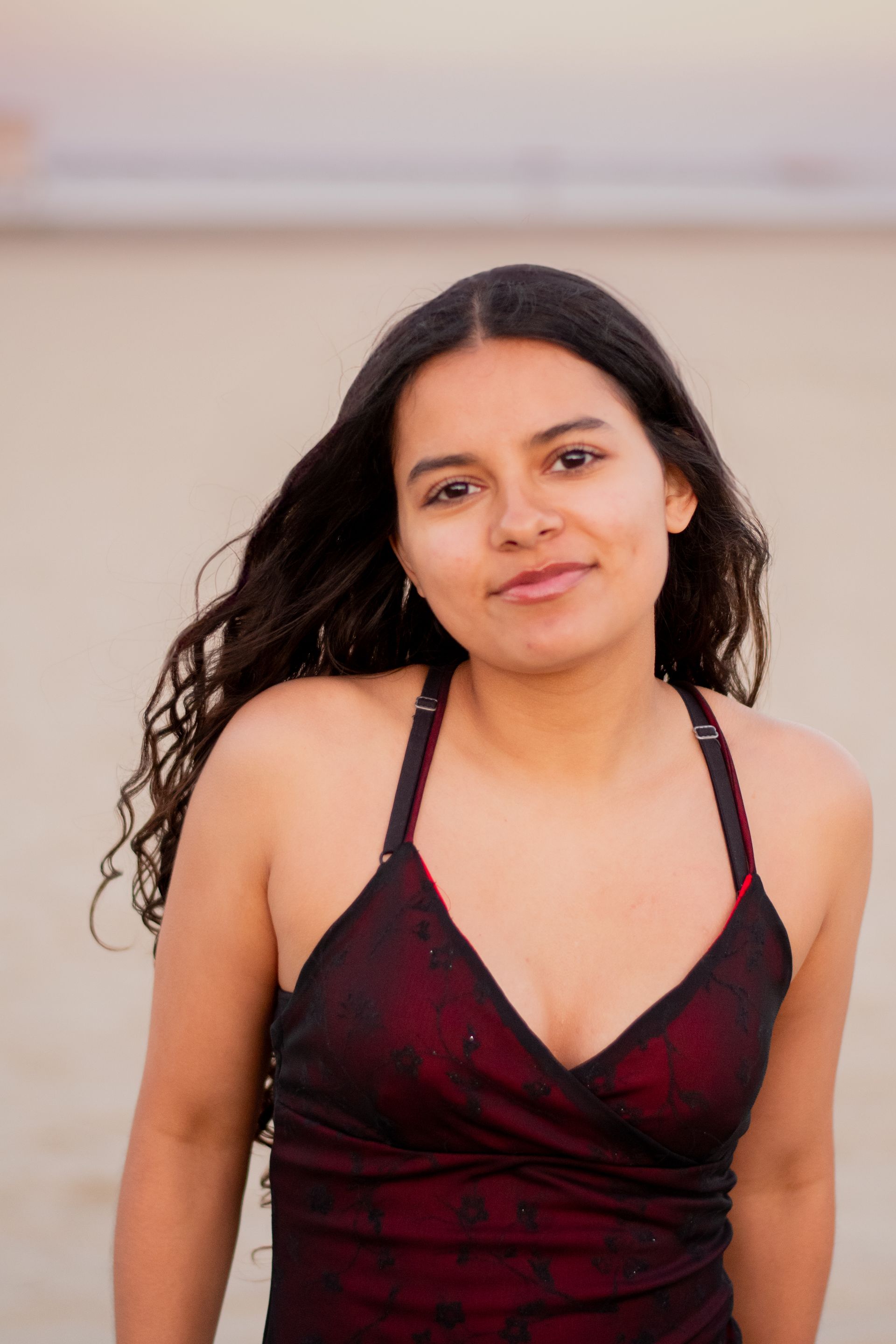 A woman in a red and black dress is standing in front of a wall near Cabrillo Beach