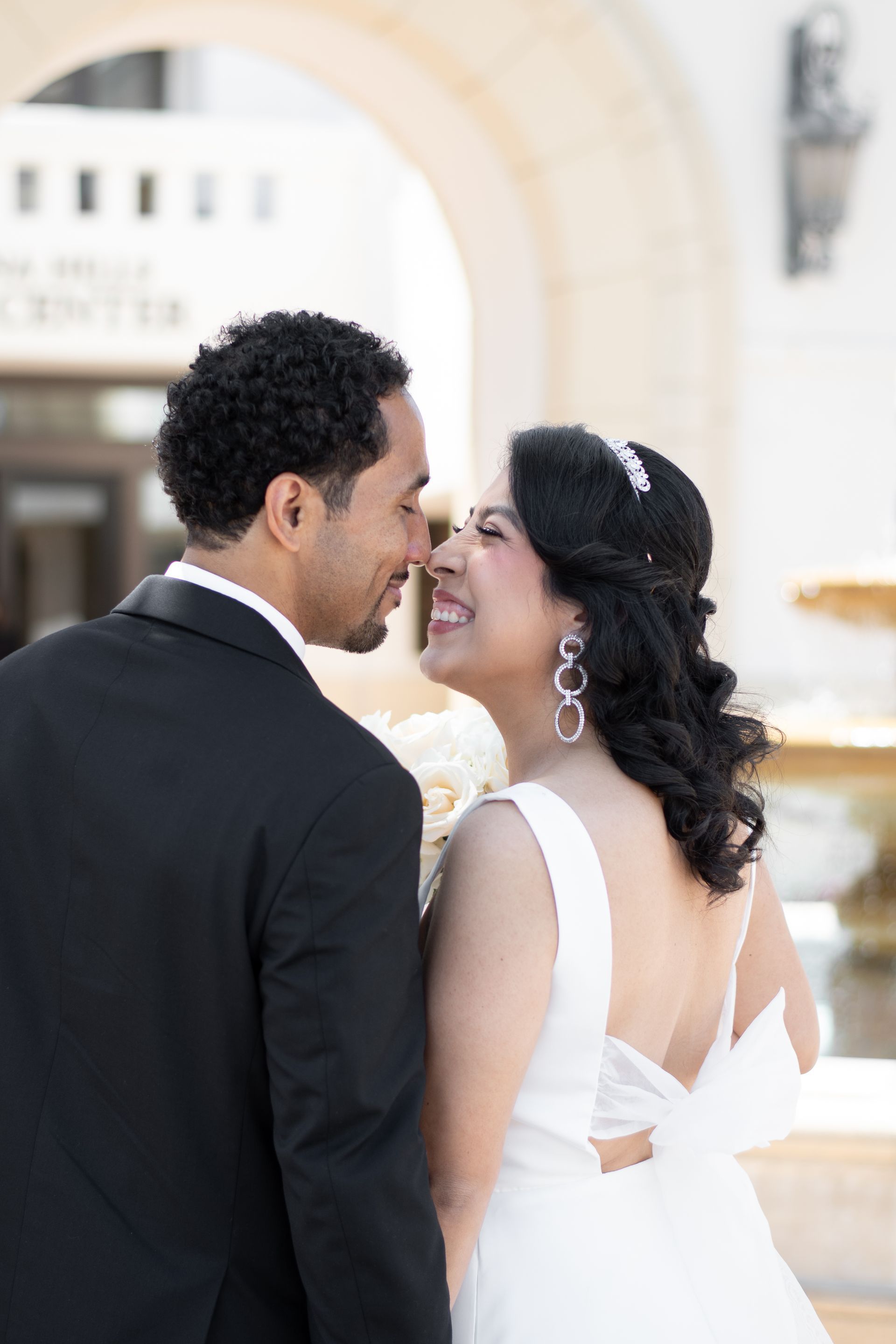 A bride and groom are looking at each other in front of a fountain in Laguna Hills, CA