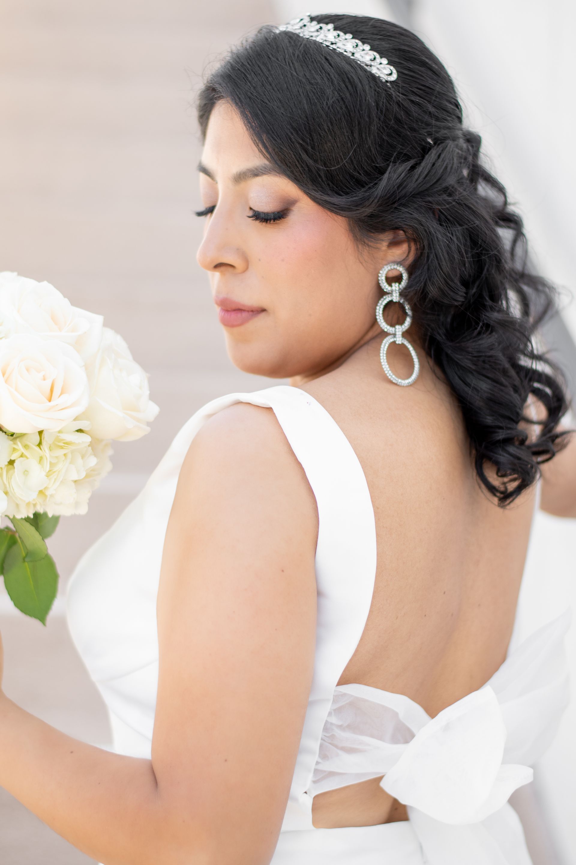 A woman in a white dress is holding a bouquet of white flowers.