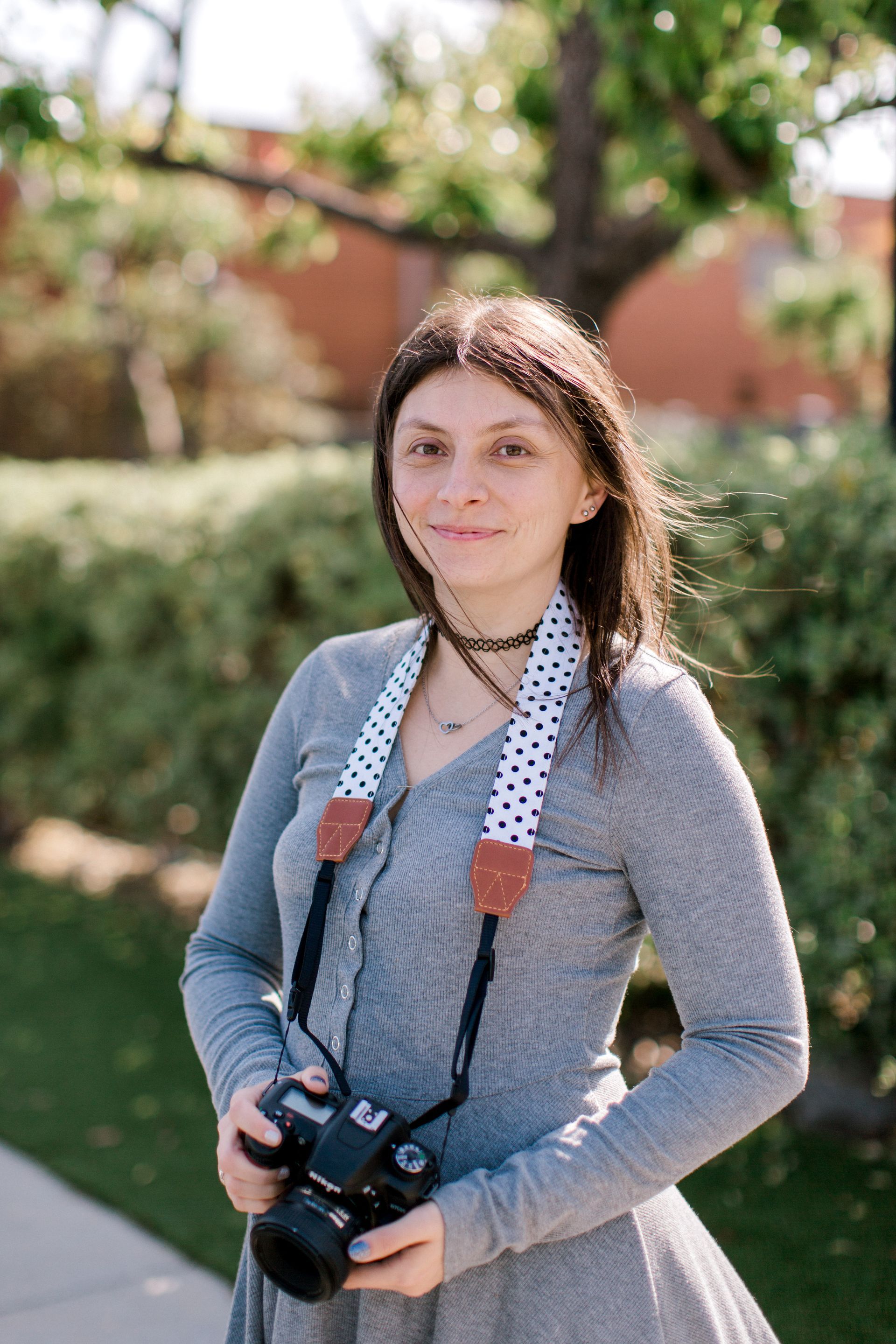 A woman is standing on a sidewalk holding a camera in El Segundo, CA.