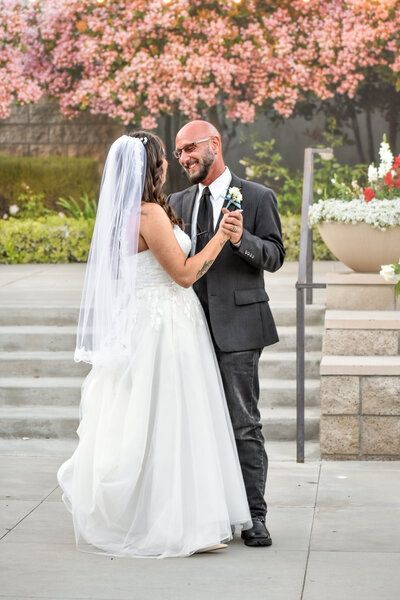 A bride and groom are dancing in front of a cherry blossom tree.