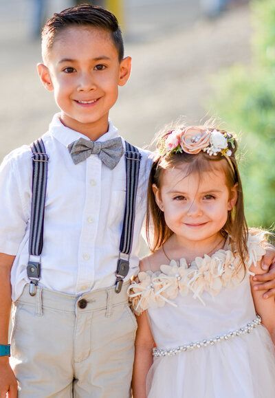 A boy and a flower girl are posing for a picture together. Siblings. Family. 