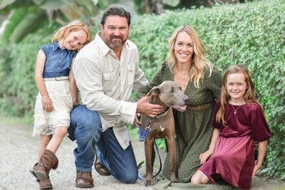 A family is posing for a picture with their dog.