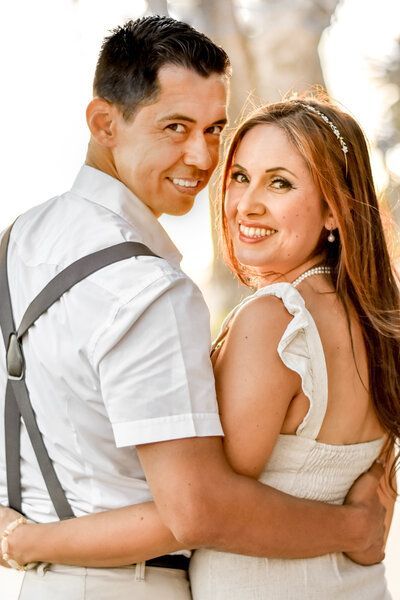 A man and a woman are hugging each other and smiling for the camera.