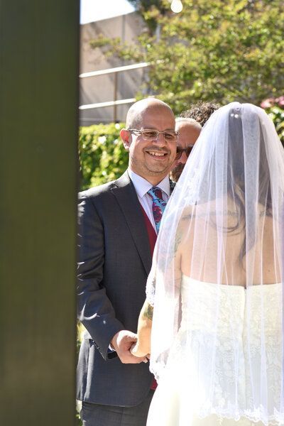 A man in a suit and tie stands next to a bride in a wedding dress