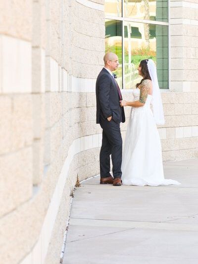 A bride and groom are standing next to each other on a sidewalk in Brea, CA