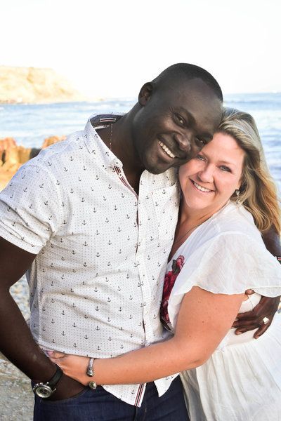 A man and a woman are hugging each other on the beach.