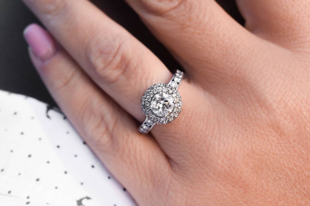 A woman is wearing a diamond ring on her left hand, engagement wedding ring