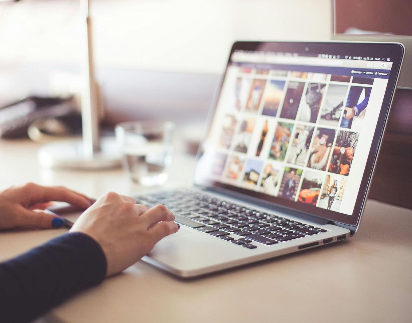 A person is typing on a laptop with pictures on the screen