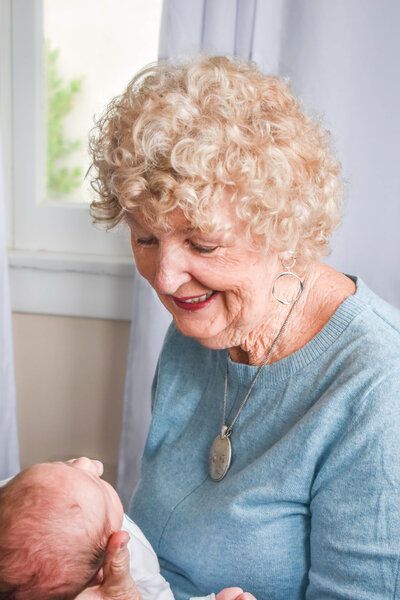 An elderly woman is holding a newborn baby in her arms. Grandma. Family.