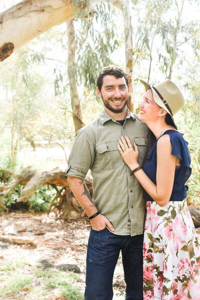 A man and a woman are standing next to each other in the woods.