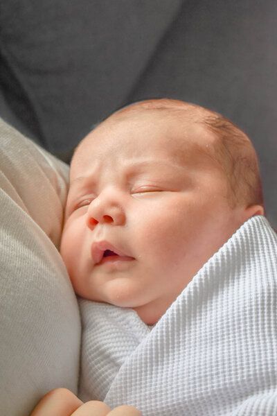 A newborn baby wrapped in a white blanket is sleeping on a pillow in Whittier.