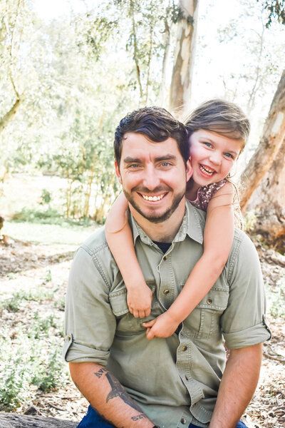 A man is carrying a little girl on his shoulders. Family
