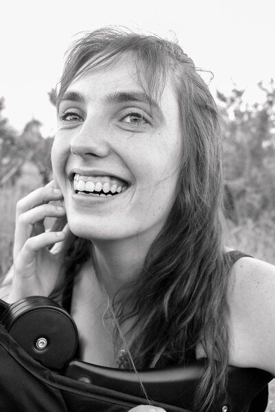 A woman is smiling while talking on a cell phone.