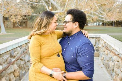 A man and a pregnant woman are looking at each other on a bridge. Maternity