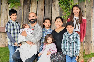 A family is posing for a picture in front of a wooden fence.