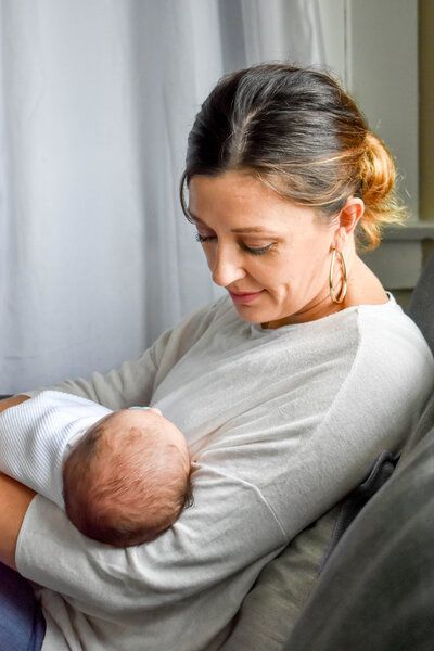 A woman is holding a newborn baby in her arms while sitting on a couch.