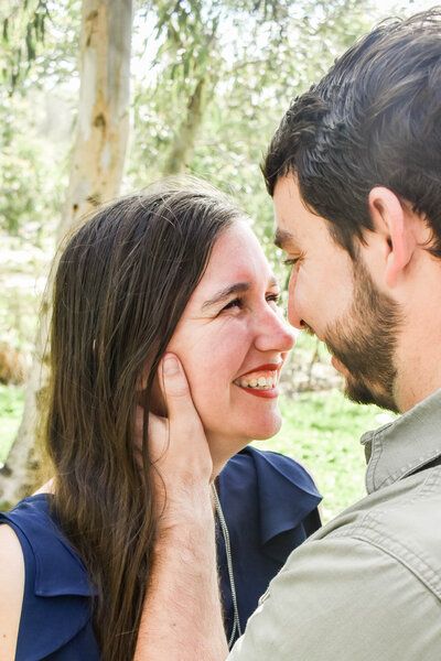 A man and a woman are looking at each other and smiling . the man is touching the woman 's face.