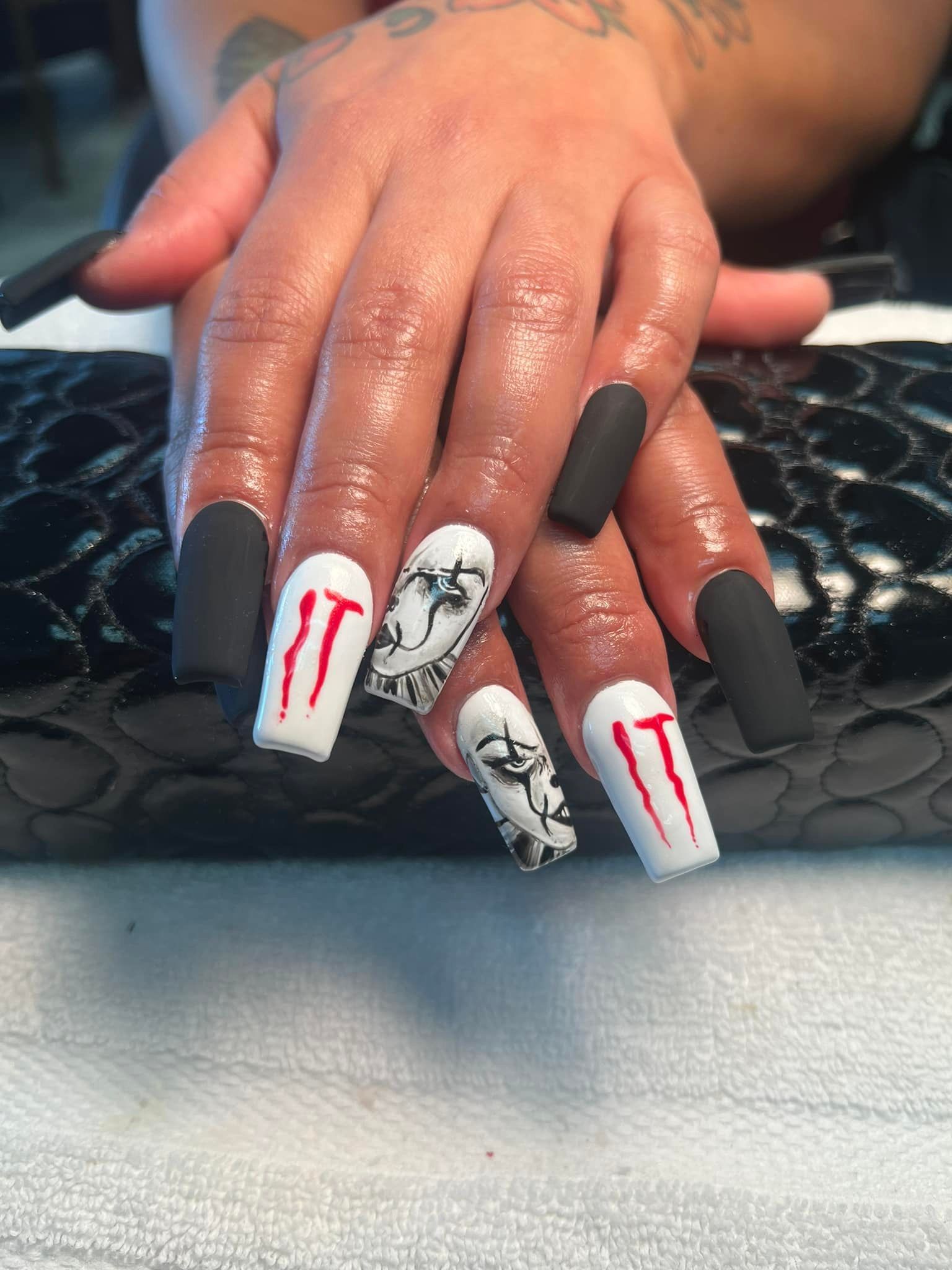 Coffin-shaped black and white nail art. Two nails feature 