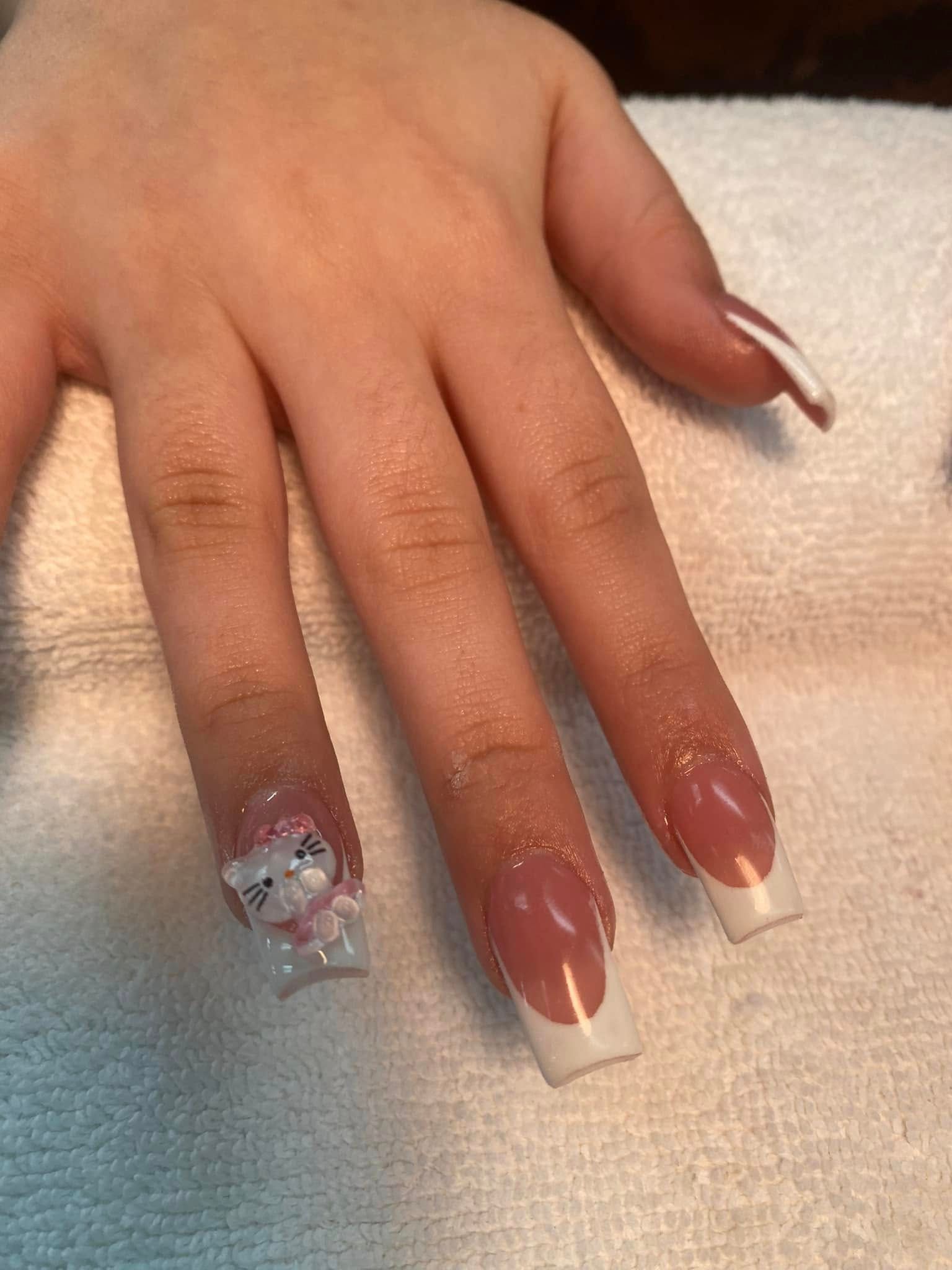 Hand with French tip and decorative nail with a small white bear, on a white cloth.