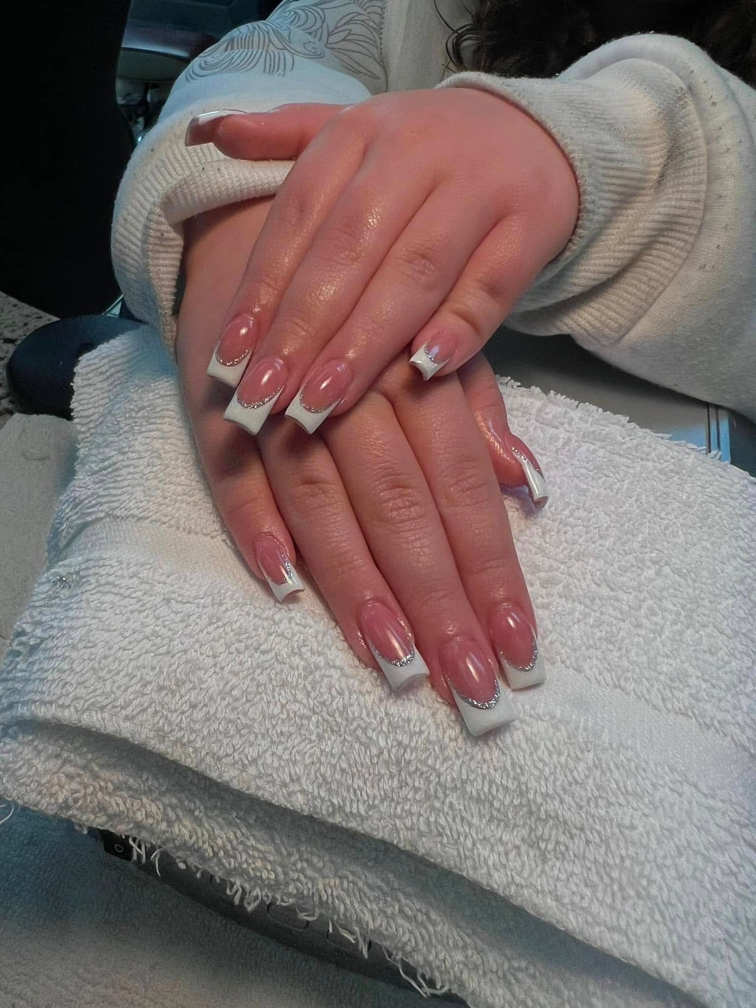 Hands with French manicure, resting on a white towel.