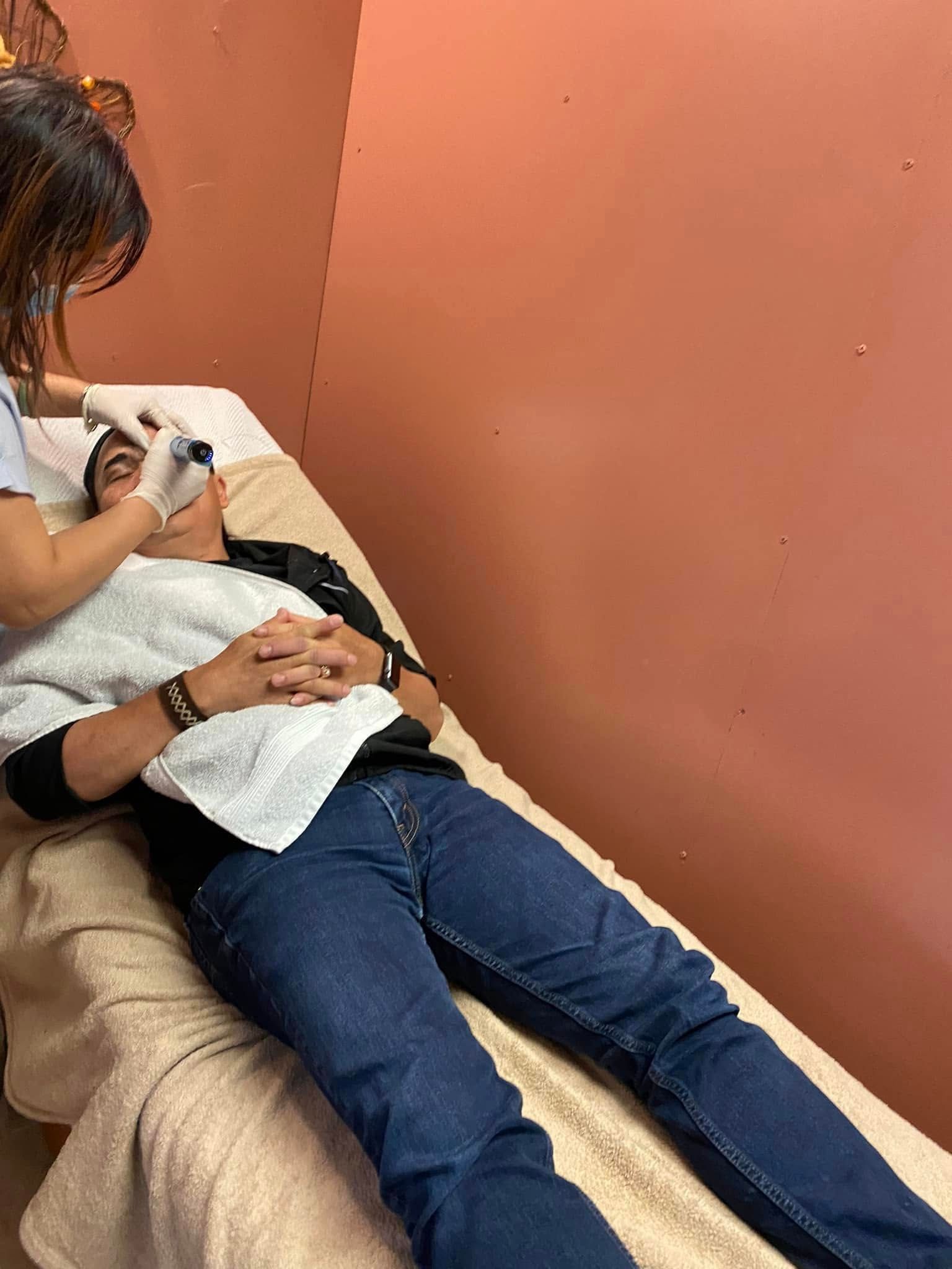 Person receiving facial treatment; spa setting, technician, and patient.