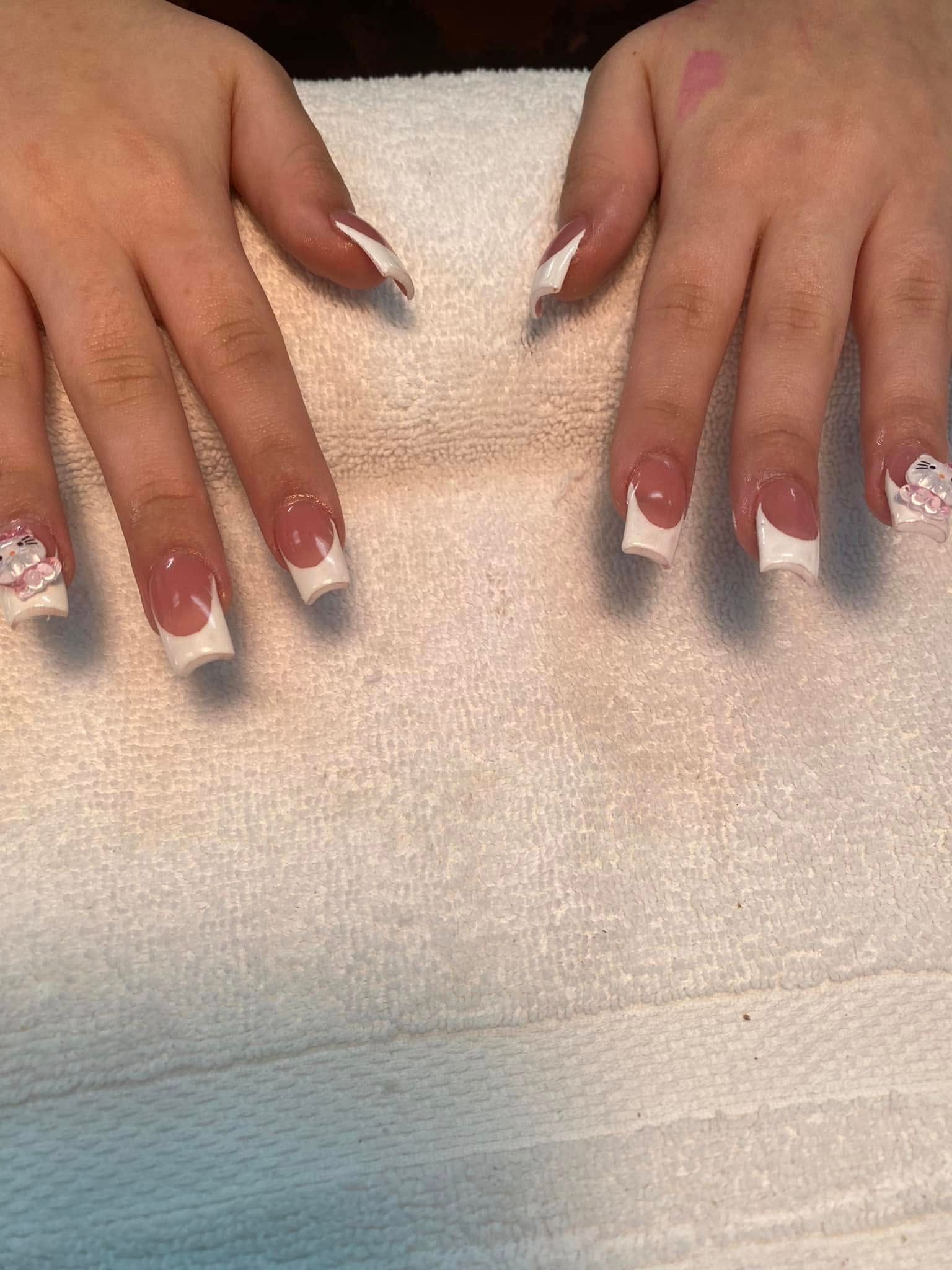 Hands with square-shaped French tip nails. One decorated nail with rhinestones.