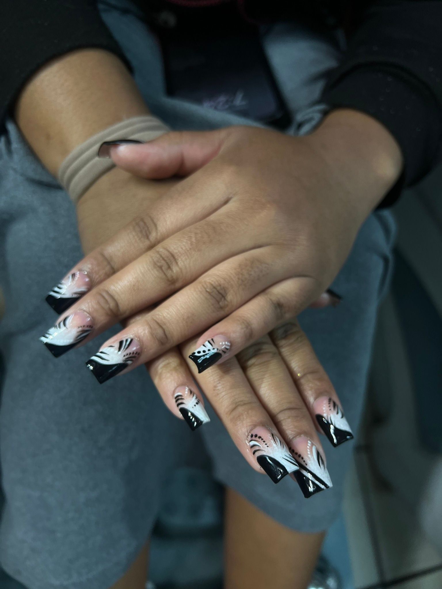 Hands with black and white patterned acrylic nails.