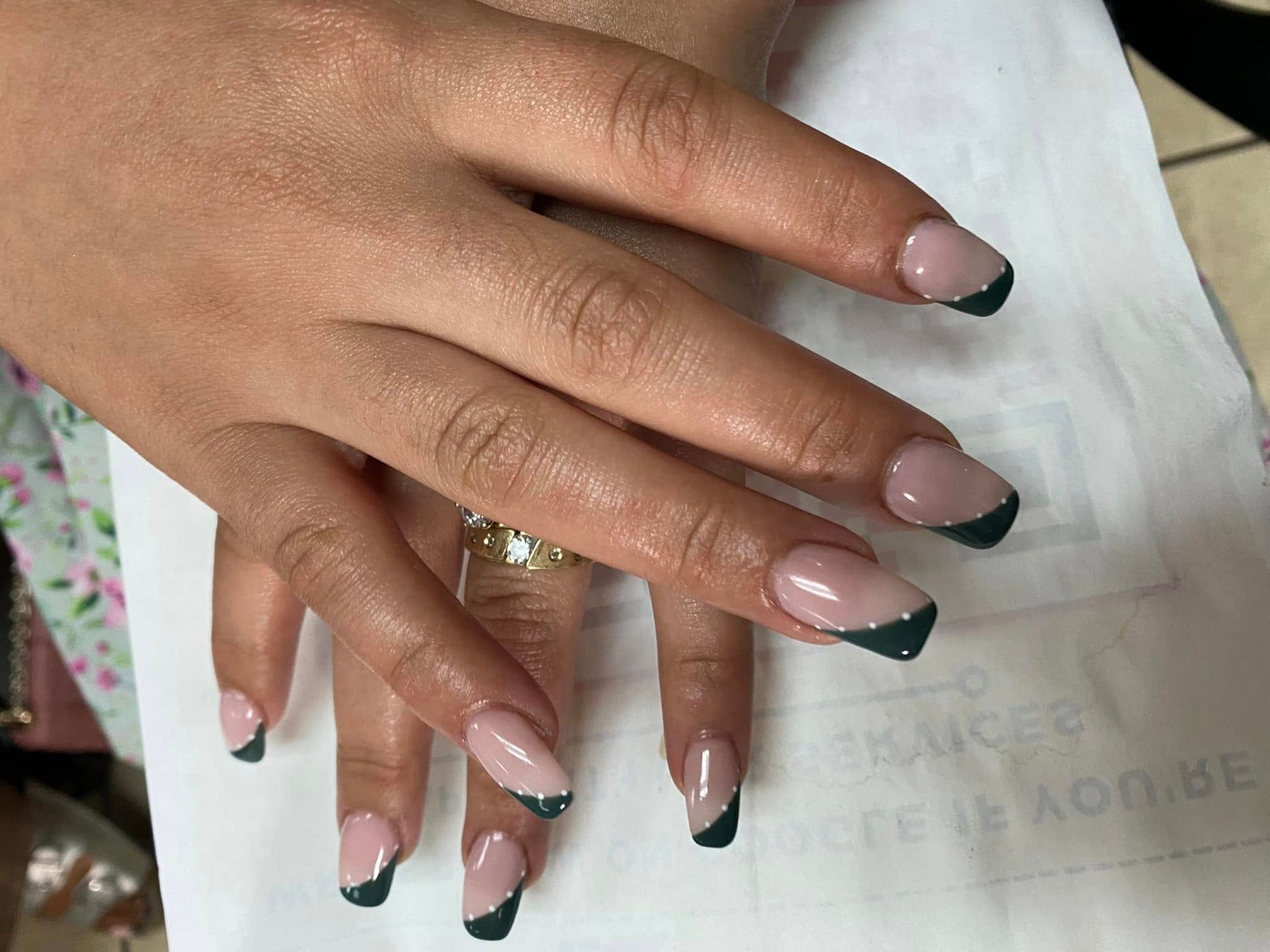 Hands with almond-shaped nails, French manicure in nude and dark green polish.
