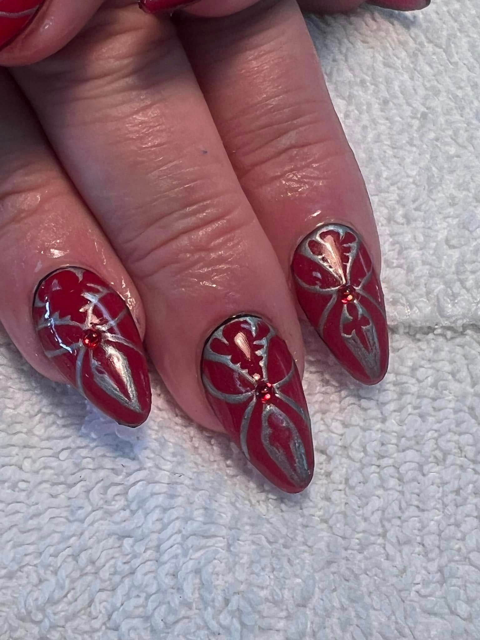 Red and silver nail art design on hand.
