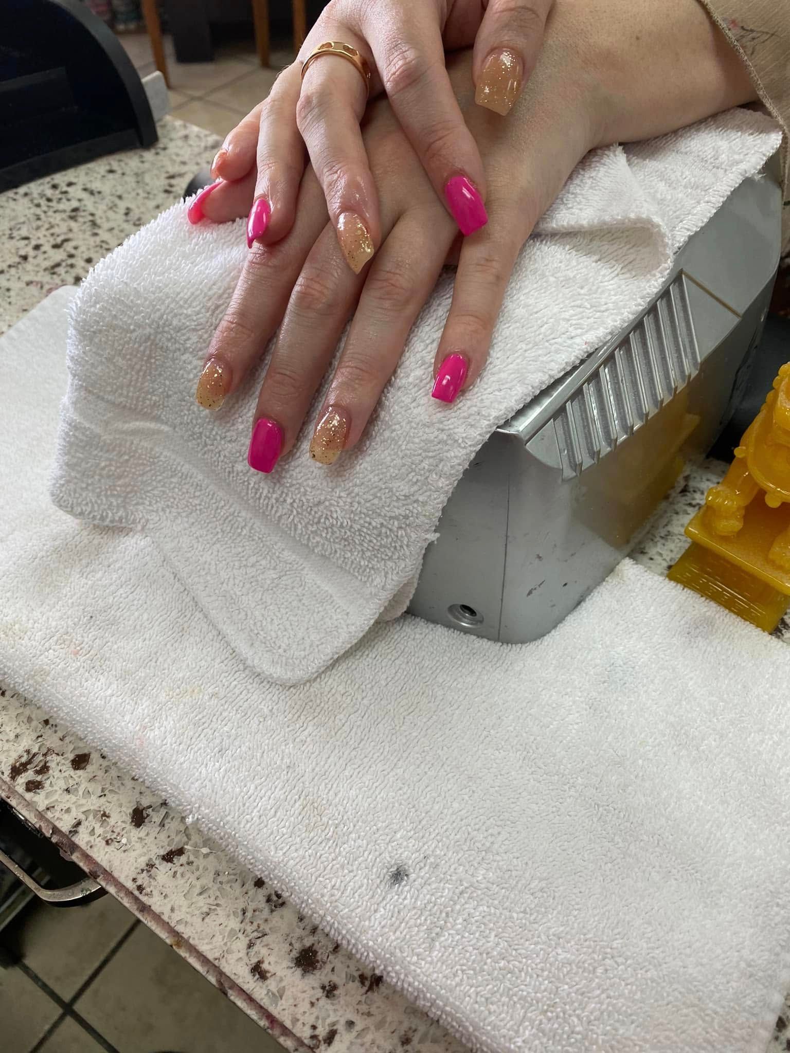 Hands with pink and tan acrylic nails resting on a white towel on a counter.