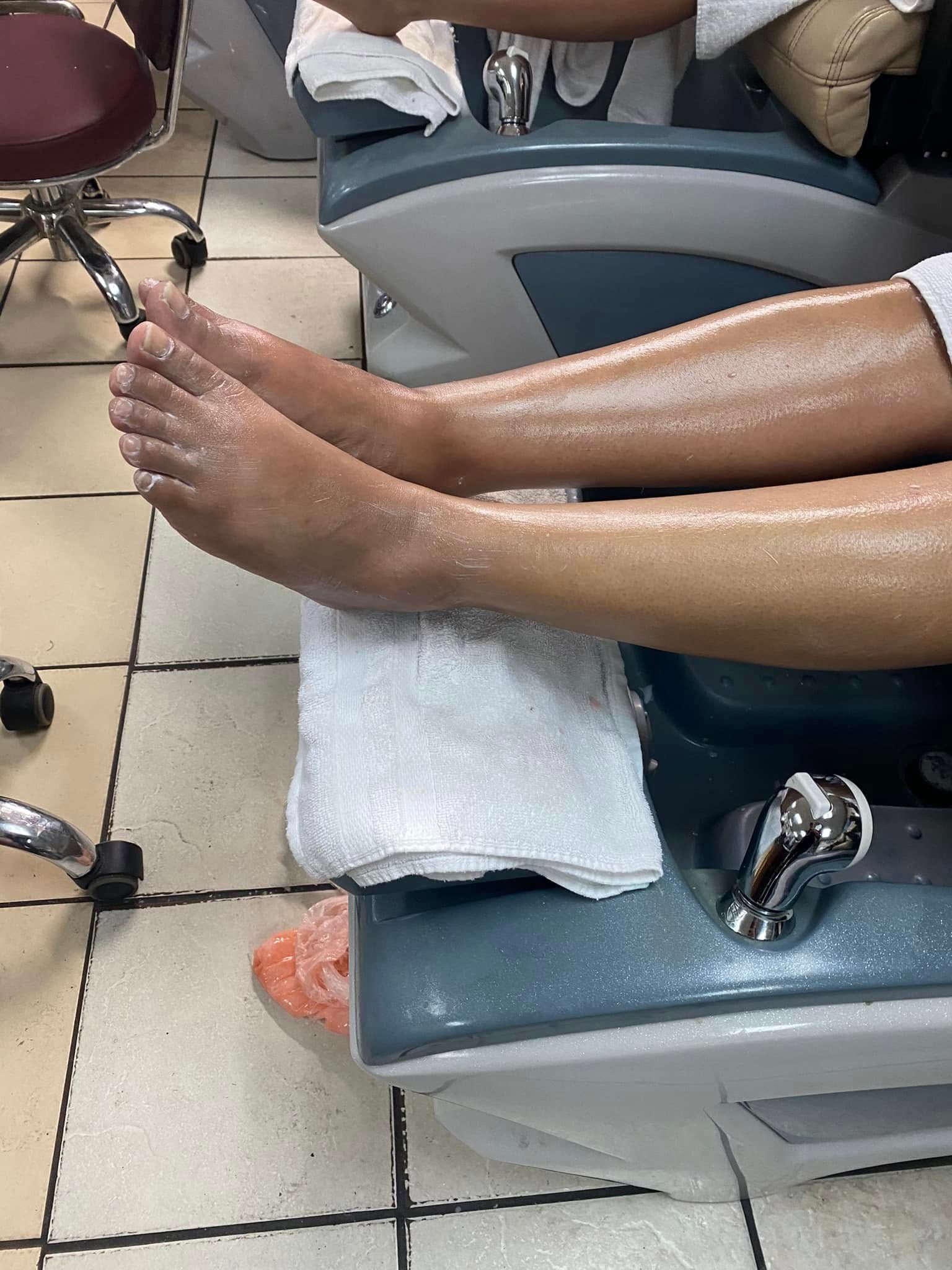 Feet in a pedicure chair, legs covered with a towel, receiving spa treatment.