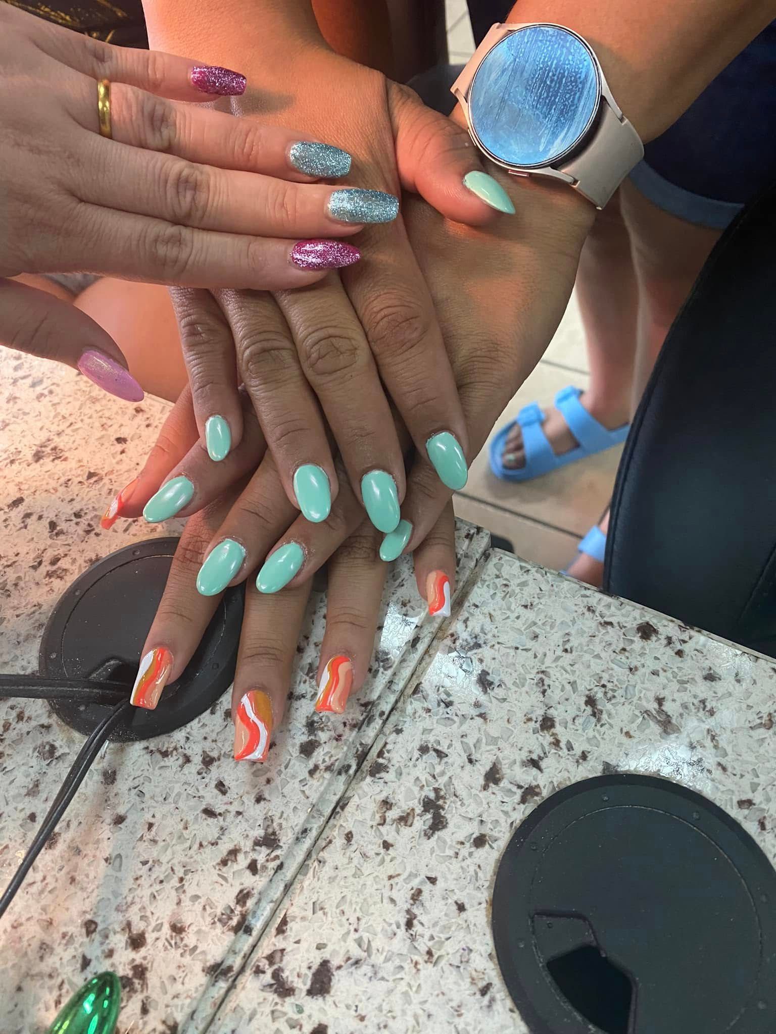 Hands with various painted acrylic nails in pastel shades, with a light-colored watch.