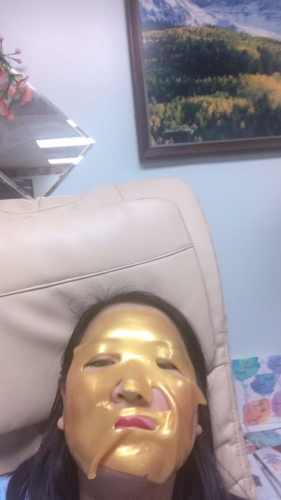 Person wearing a gold face mask in a salon setting.