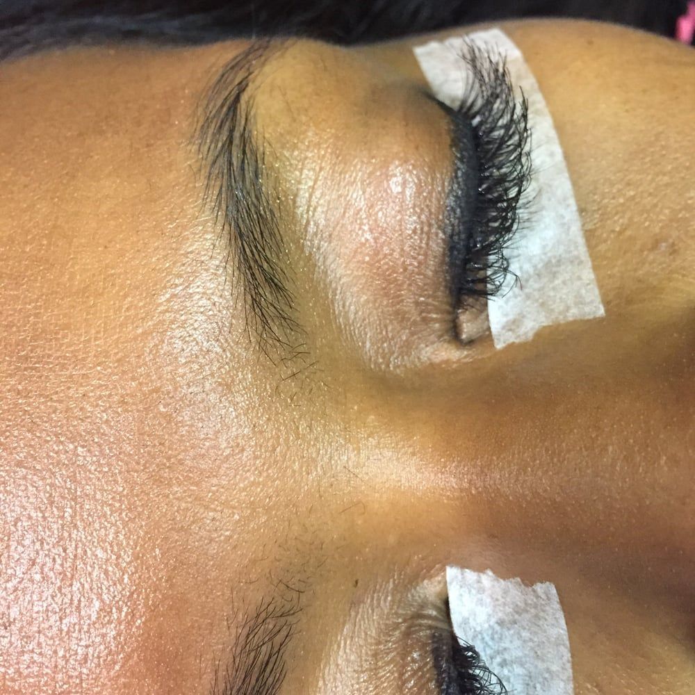 Close-up of a person's eyes with extended eyelashes, secured with white tape.