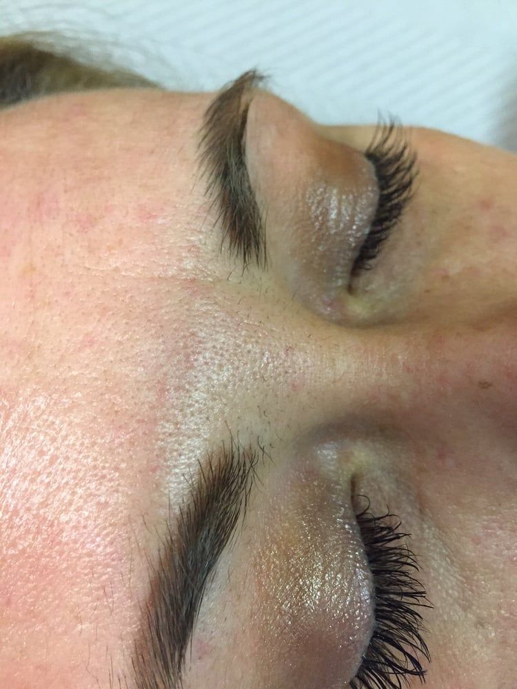 Close-up of closed eyes with dark, full eyelashes and arched eyebrows, on fair skin.