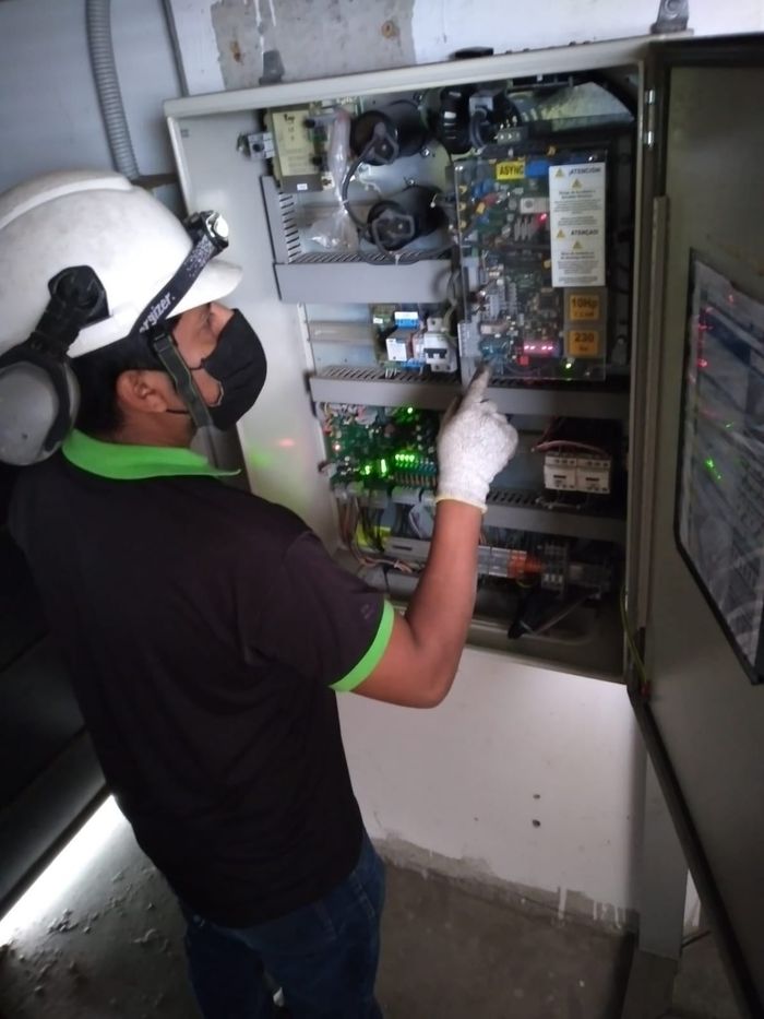 Un hombre con máscara y casco está trabajando en una caja eléctrica